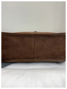 Detail of the brown suede bucket bag featuring reinforced stitching and leather piping
