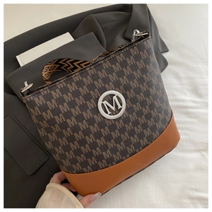 Close-up of brown bucket bag with M-letter print, metal logo, and wide fabric strap