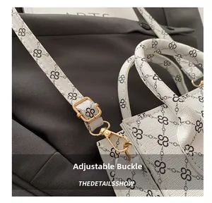 Detail of adjustable gold buckle and chain logo print on white leather handbag strap
