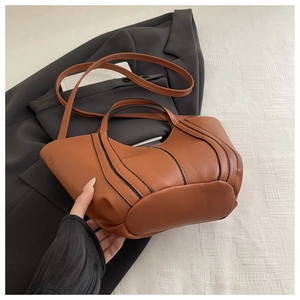 Detailed view of caramel brown bucket bag with black trim and cylindrical handles