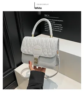 Detail view of white quilted crossbody bag with gold Fashion text and metallic lock