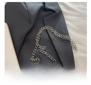 Detail shot of a silver hardware chain strap on an orange leather handbag with texture