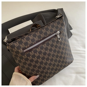 Close-up of brown crossbody bag with M-letter print and geometric woven strap