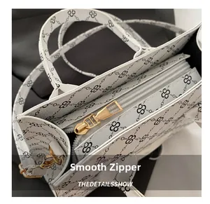 Detail of smooth gold zipper on a white monogram tote bag with high-quality hardware