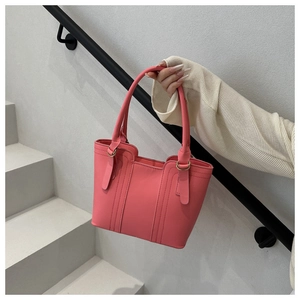 Detailed view of pink leather tote bag with vertical stitching and gold ring hardware