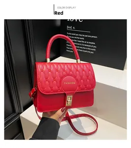 Detail of red quilted faux leather handbag with golden lock and Fashion emblem