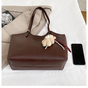 Détail du sac cabas marron foncé en similicuir avec texture grainée et ours peluche