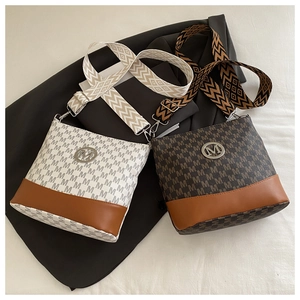 Macro view of patterned bucket bag showing letter prints and metallic M logo detail