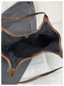 Macro shot of spacious black tote interior with magnetic buckle and brown leather straps