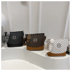 Three bucket bags with M-print pattern and geometric webbing straps on white podium