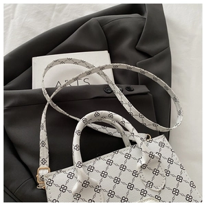Detailed close-up of white crossbody bag with geometric chain print and gold metal buckle