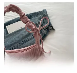 Pink corduroy bag detail showing ruffled strap with bow and silver metal zipper