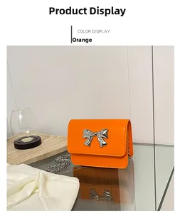 Close-up of orange PU leather mini bag with silver metal bow and delicate chain strap