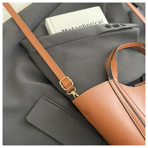 Detail of caramel leather handbag with adjustable strap and premium gold buckle hardware
