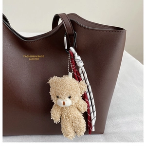 Détail du cabas en cuir marron foncé avec texte doré et porte-clés ours en peluche mignon