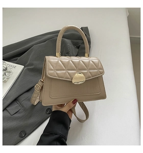 Vue détaillée du sac beige avec rabat matelassé, texture crocodile et fermoir doré