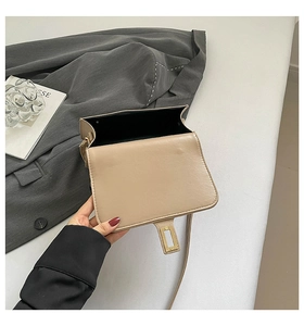 Top view of beige flap shoulder bag with gold hardware on a grey suit jacket