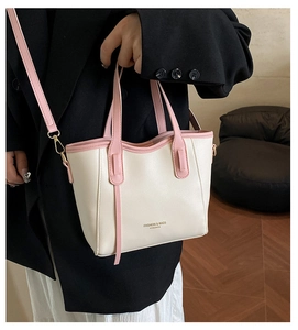 Detail of a cream and pink bucket bag showing golden lettering and leather texture