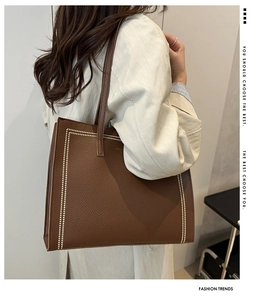 Détail du sac cabas en cuir marron grainé avec des surpiqûres verticales blanches