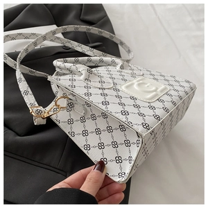 Detail of white PU leather bag with black logo print and gold hardware on blazer