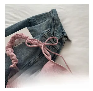 Detail of pink corduroy handbag featuring pleated handles and decorative bow ribbons