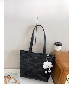 Détail du sac cabas tressé noir avec plaque dorée et pendentif nuage blanc mignon