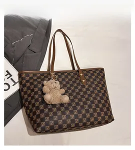 Detail of dark brown tote bag with retro Z-pattern checkerboard and bear pendant