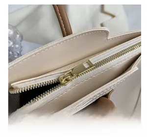 Close-up of smooth gold zipper hardware and cream synthetic leather on minimalist tote bag