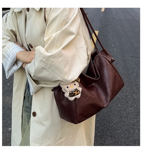 Detail of dark brown leather tote bag with RICHAD engraving and plush leopard charm