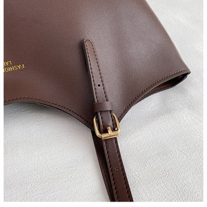 Détail de la texture en cuir et boucle dorée sur un sac cabas marron tendance
