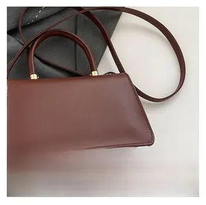 Close-up of a deep brown structured handbag with golden metal hardware and a top handle
