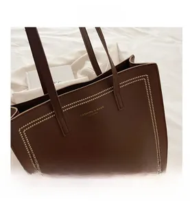 Gros plan du sac cabas en cuir marron avec motif litchi, surpiqûres et logo doré chic
