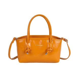 Chic orange glossy handbag with dual handles and long shoulder strap in vibrant finish