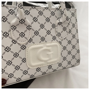 Detail shot of white textured leather surface with clover patterns and G logo emblem