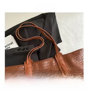 Close-up of brown woven tote bag with leather straps and metal rivets on suit jacket