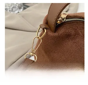 Close-up of golden metal hooks and zipper on a brown suede vintage shoulder bag