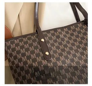Close-up of brown tote bag with M-pattern monogram and gold metal rivet hardware
