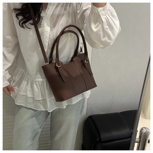 Detail of dark brown matte leather tote with double handles and slim shoulder strap