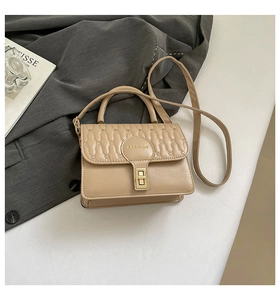 Detail of light khaki shoulder bag with wave quilting and golden twist lock closure