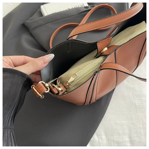 Detail view of brown patchwork handbag featuring cream canvas insert and slim shoulder strap