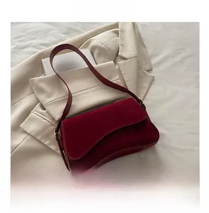 Detail view of burgundy suede crescent bag with adjustable strap and flap closure