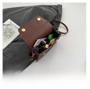Detail view of brown leather crossbody bag showing interior storage for phone and lipstick