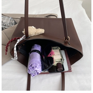 Intérieur spacieux d'un cabas en cuir marron avec parapluie, lunettes et parfum