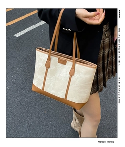 Detail showing the cream canvas and brown leather trim of this large tote bag on a model