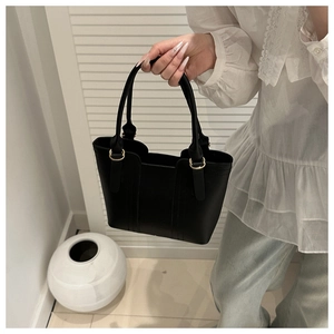 Detail of elegant black leather handbag with gold metal rings and minimalist stitching