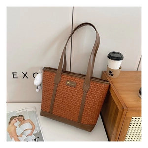 Détail du sac cabas à carreaux avec anses en cuir marron et breloque pompon blanc en peluche
