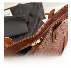 Detail of smooth gold zipper on brown checkered woven tote bag with premium lining