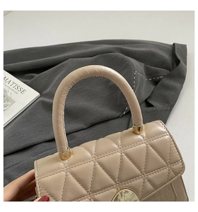 Détail d'un sac matelassé beige avec ferrures dorées et texture crocodile élégante