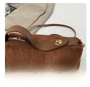 Detailed macro view of high-quality golden metal turn-lock on a brown suede handbag