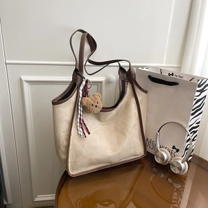 Minimalist beige bucket bag with brown leather trim and cute bear charm pendant